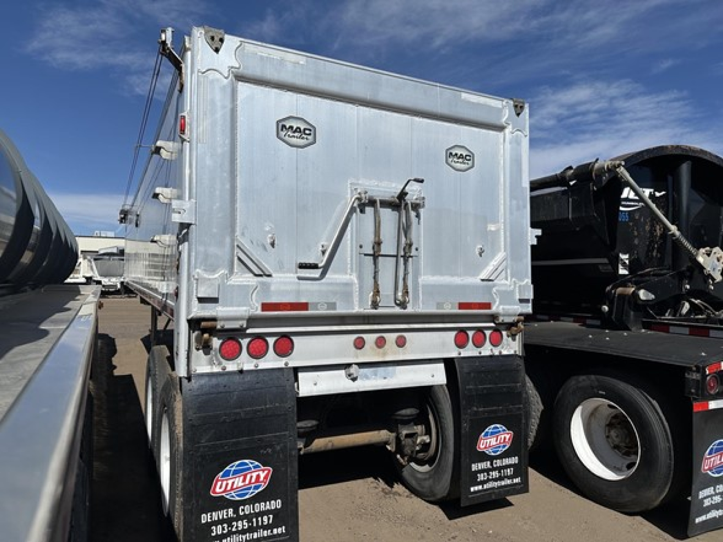 Dump trailer rear showing MAC logo doors and lights, with rear bumper and mud flaps.