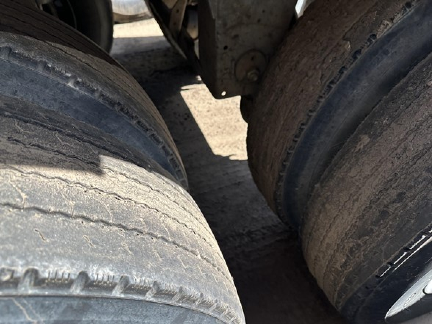 Trailer tires and wheel area of a Mac Mvp dump trailer showing worn tread and dual axle tires.