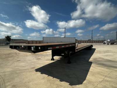 Trailer: 53' drop deck with closed tandem ramps in open lot, side rails, landing gear, and reflectors visible.