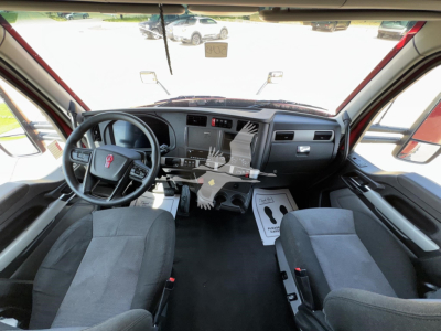 Kenworth T680 cab interior showing steering wheel and dashboard with center console and seats.
