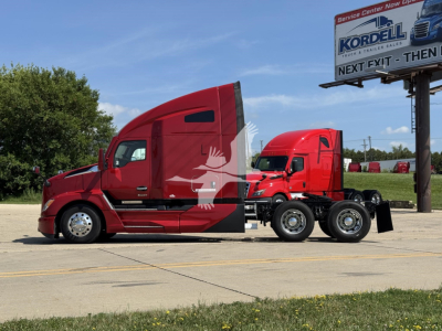 Kenworth T680 tractor with red cab and sleeper, side view showing attached trailer chassis; 2023 model