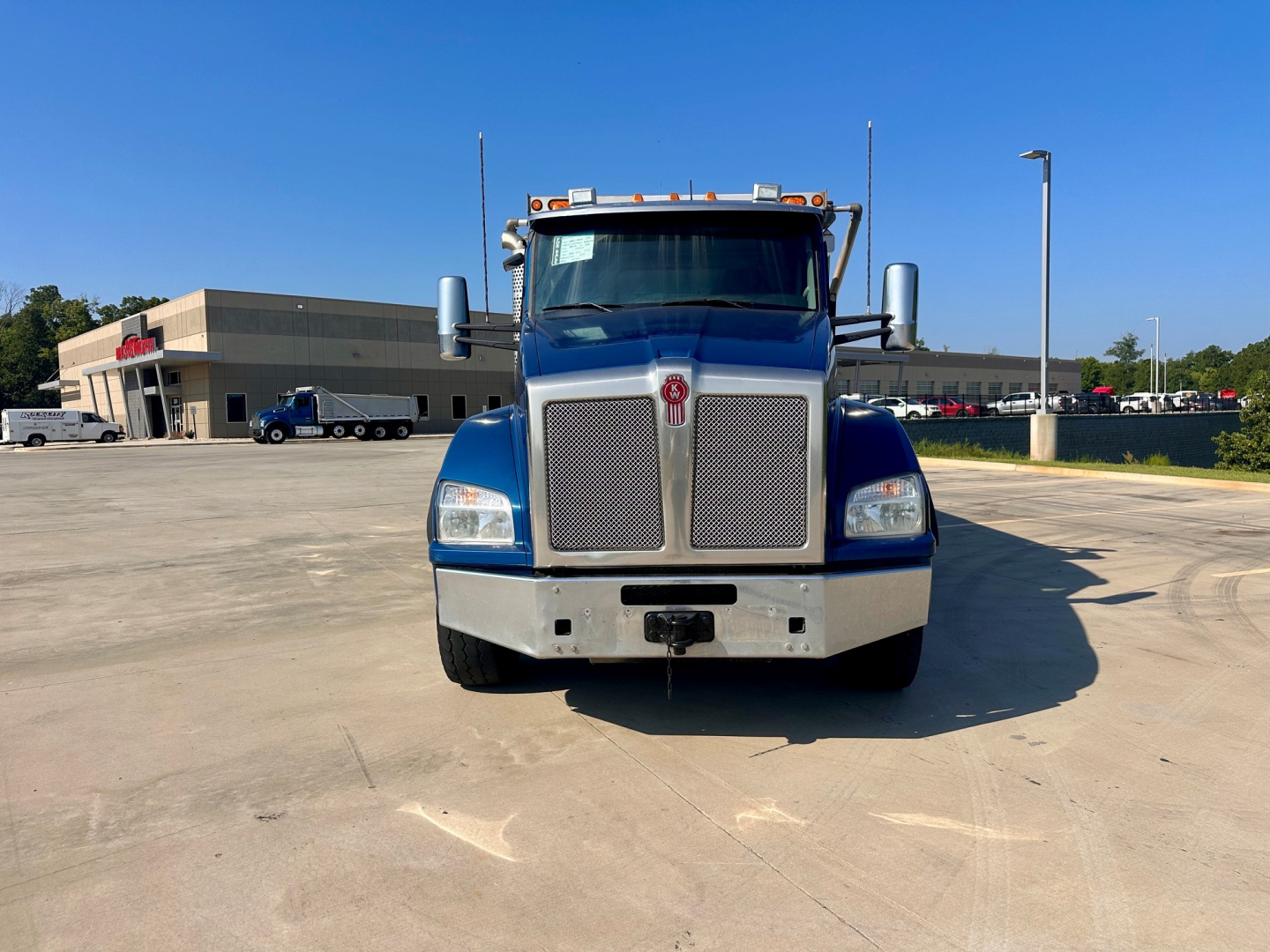 Truck front view of a blue 2021 Kenworth T880 dump truck showing large grille, bumper, headlights, and mirrors.