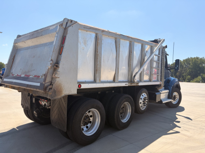 Kenworth T880 dump truck side rear showing dump bed and dual rear axle configuration.