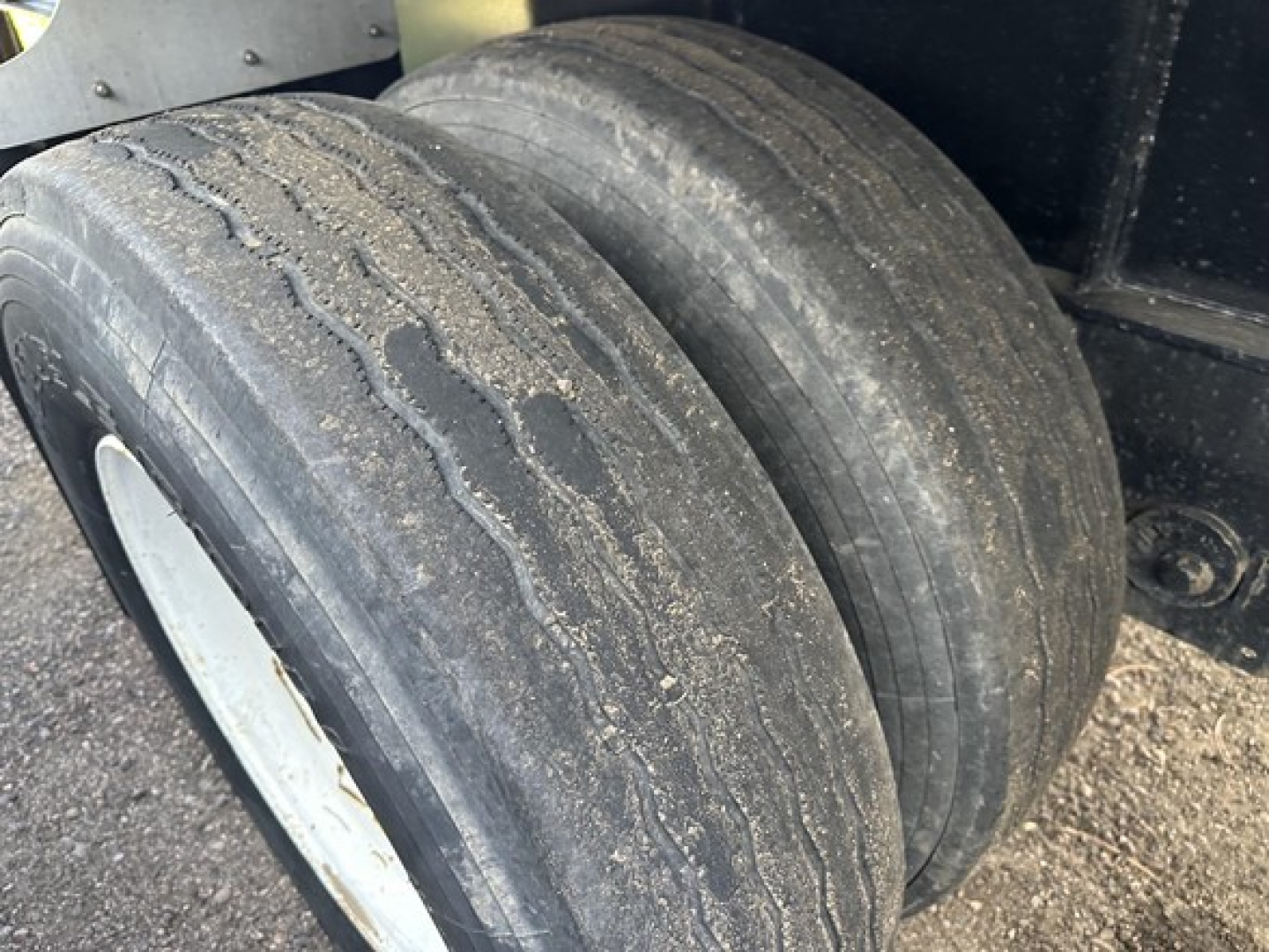 Dual rear tires of a Transcraft spread air combo flatbed trailer showing worn tread and sidewall details.