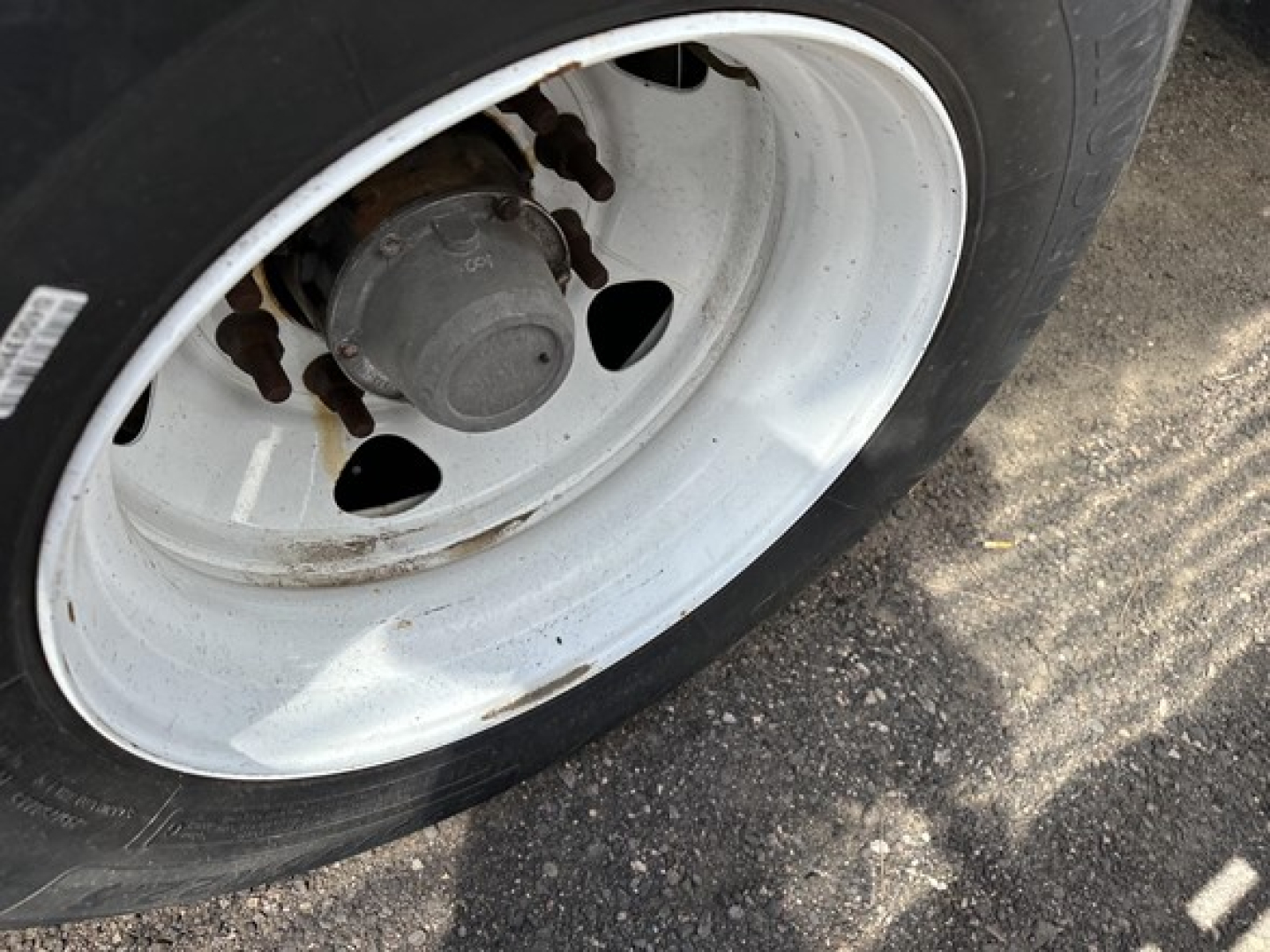 Wheel close-up of trailer axle on a 2020 Transcraft spread air combo flatbed showing white rim and hub.