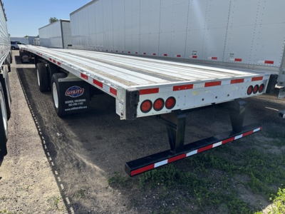 Flatbed trailer showing 2020 Transcraft spread air combo with dual axles and reflective tape along sides and rear.