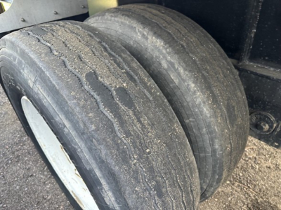 Dual rear tires of a Transcraft spread air combo flatbed trailer showing worn tread and sidewall details.