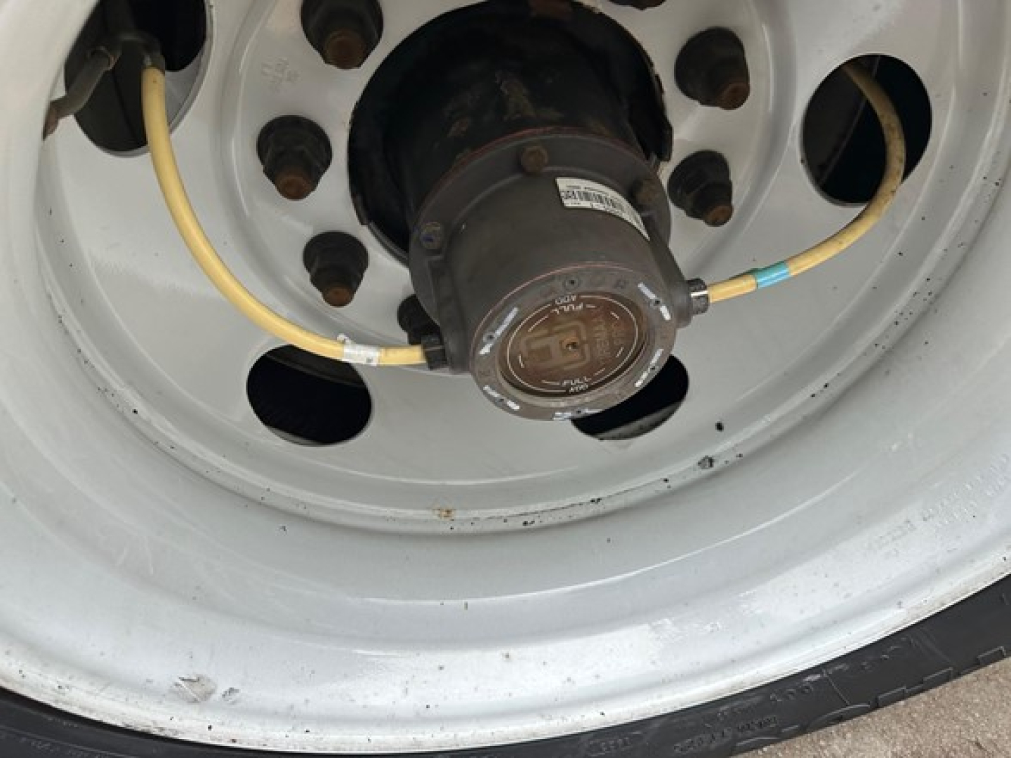 Trailer wheel hub showing axle hub with attached electrical wiring and tire rim.