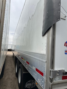 Utility 4000Dx trailer side view showing riveted aluminum wall, corner corner post, and wheel set with dual axles.