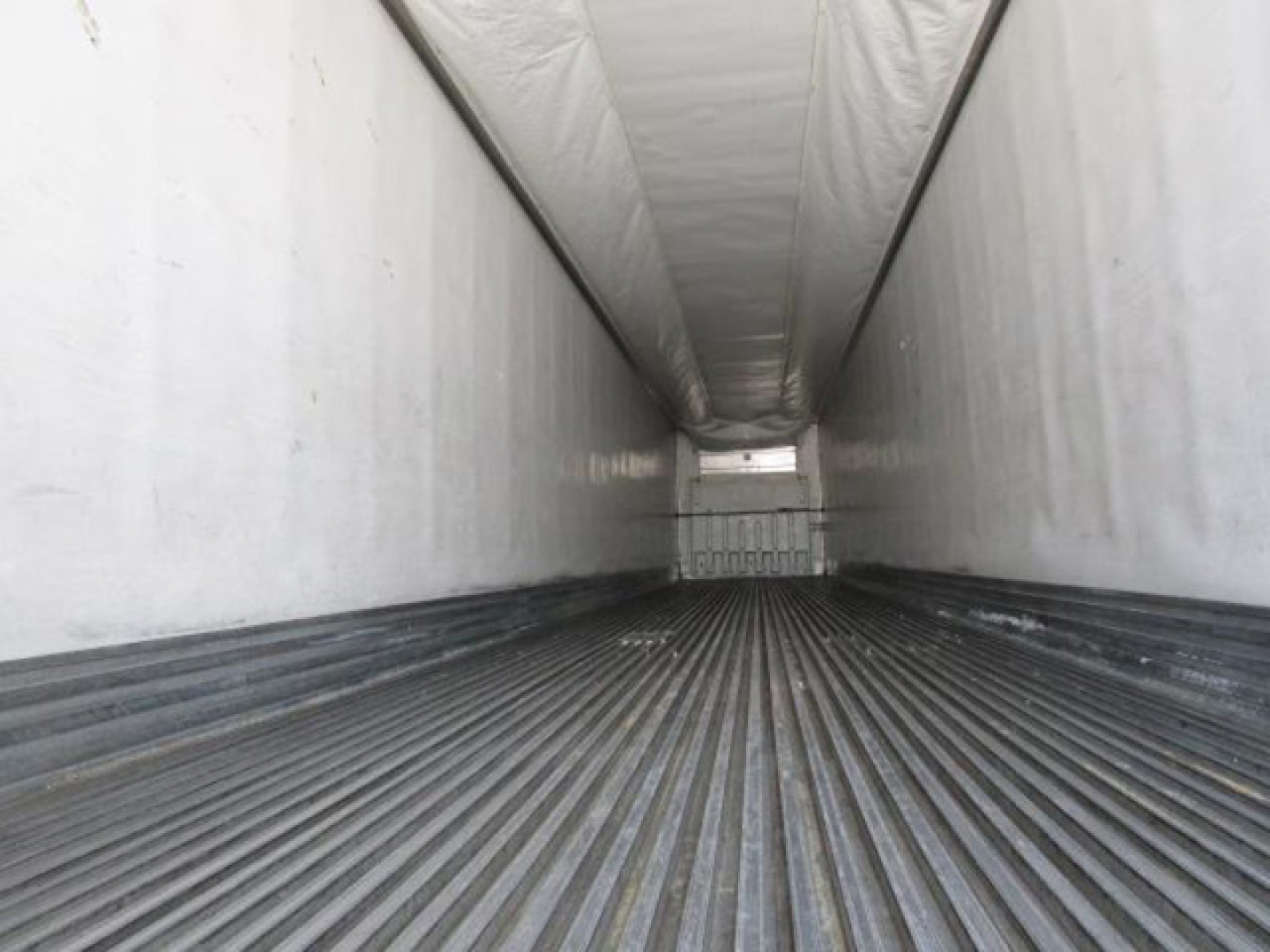 Trailer interior showing empty refrigerated trailer with ribbed floor and white sidewalls, long narrow cargo area.