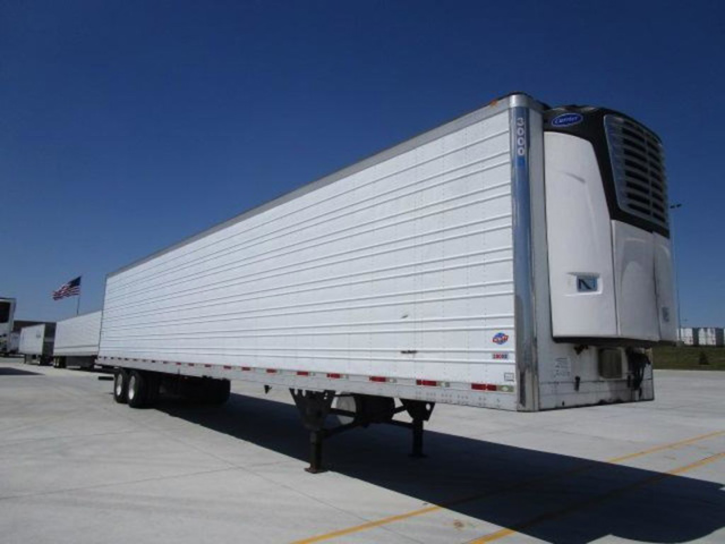 Trailer refrigerated utility trailer with a front-mounted cooling unit, raised landing gear, and white aluminum side panels.