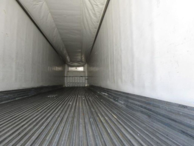Trailer interior showing long refrigerated cargo area with ribbed floor and white walls, empty bay.