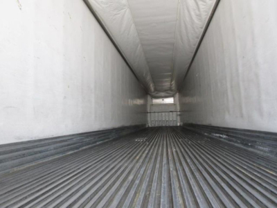 Trailer interior showing empty refrigerated trailer with ribbed floor and white sidewalls, long narrow cargo area.