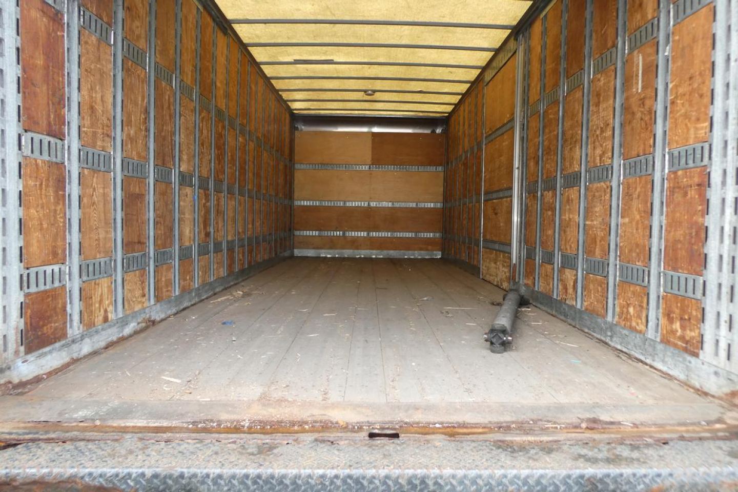 Truck cargo area of a 2006 International 4300 SBA with empty box interior showing wooden side walls and a metal floor.