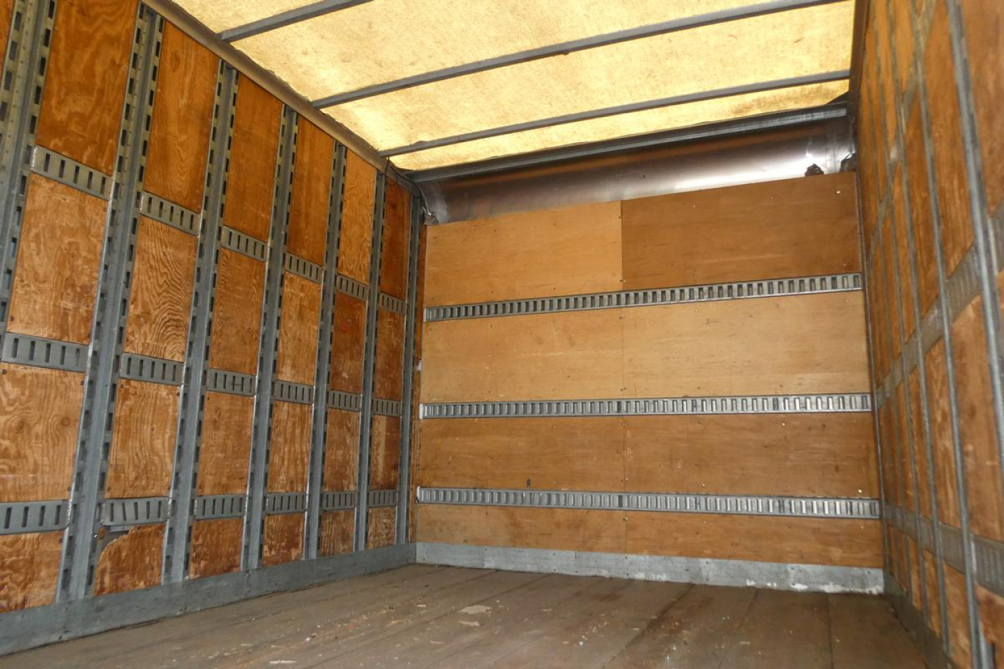 Truck cargo area of a 2006 International 4300 SBA box truck showing wooden interior walls and metal runners.