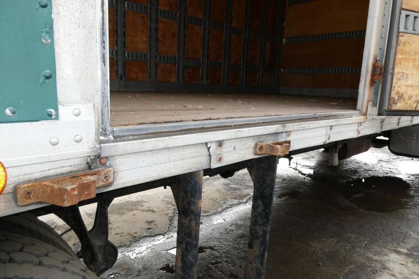 View of the lower box truck side of a 2006 International 4300 SBA showing open cargo bay with metal ramps and support braces.