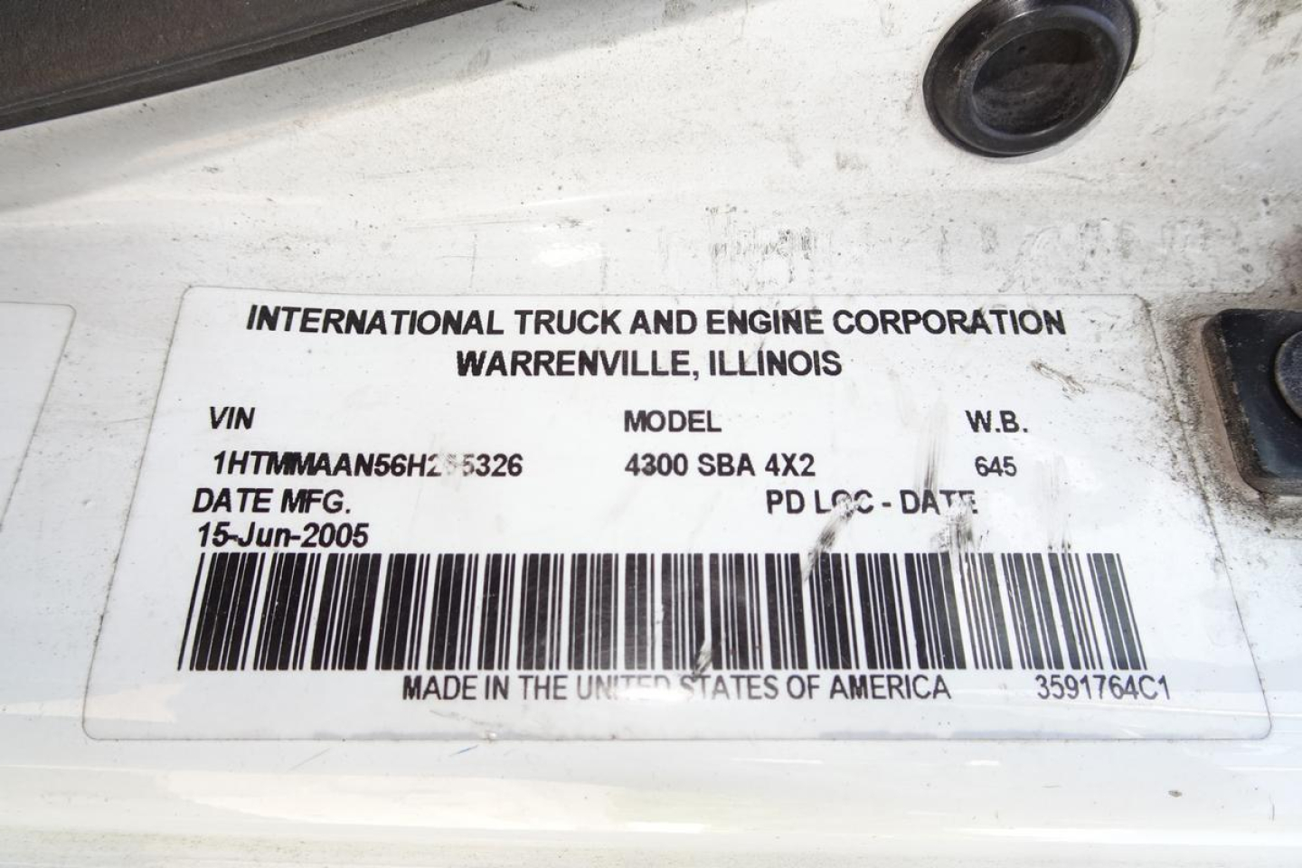 Label on International truck showing VIN, model, and date: INTERNATIONAL TRUCK AND ENGINE CORPORATION WARRENVILLE ILLINOIS; VIN 1HTMMAAN56H255326; MODEL 4300 SBA 4X2; PD LOC DATE; MADE IN THE UNITED STATES OF AMERICA.