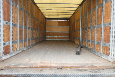 Truck cargo area of a 2006 International 4300 SBA with empty box interior showing wooden side walls and a metal floor.