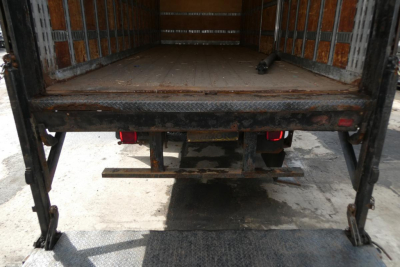 International 4300 SBA truck bed interior showing flat wooden floor and rear underride guard with hitch. Image focuses on cargo area and tail end.
