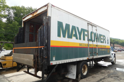 Box truck side with MAYFLOWER MCCOLLINS TRANSITATION SERVICE text; rear loading ramp; Mayflower Logistics box; Mayflower logo visible.