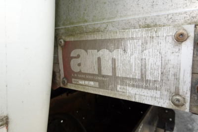 Amco or A.M. Hare body company plate on side of truck showing logo and worn metal plate with screws.