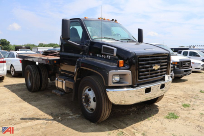 Chevrolet Kodiak C7500 stake dump truck shown in a dirt lot, front-left view with dual mirrors and chrome bumper.