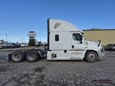 Truck side view showing 2016 Freightliner Cascadia conventional sleeper with white cab and dual rear axles.