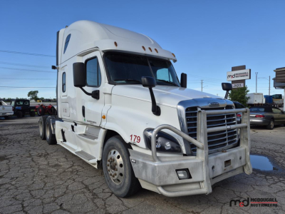 Truck: 2016 Freightliner Cascadia Conventional Sleeper tractor in white, front grille guard, dual rear axles, side mirrors, cab with tall sleeper, VIN plate and numbers on door, dealership lot in background.