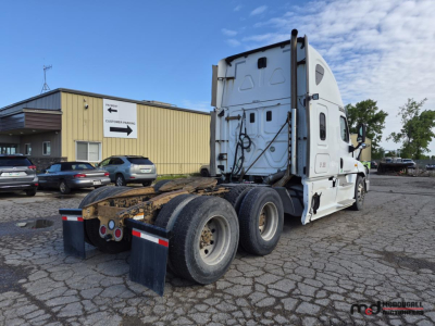 Truck rear view showing fifth wheel and dual rear axles on Freightliner Cascadia semi-truck in parking lot.