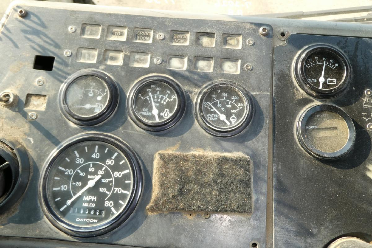 Kalmar Ottawa YT30 truck dashboard panel showing multiple gauges including MPH speedometer and various switches; dusty metal panel with worn cover plate.
