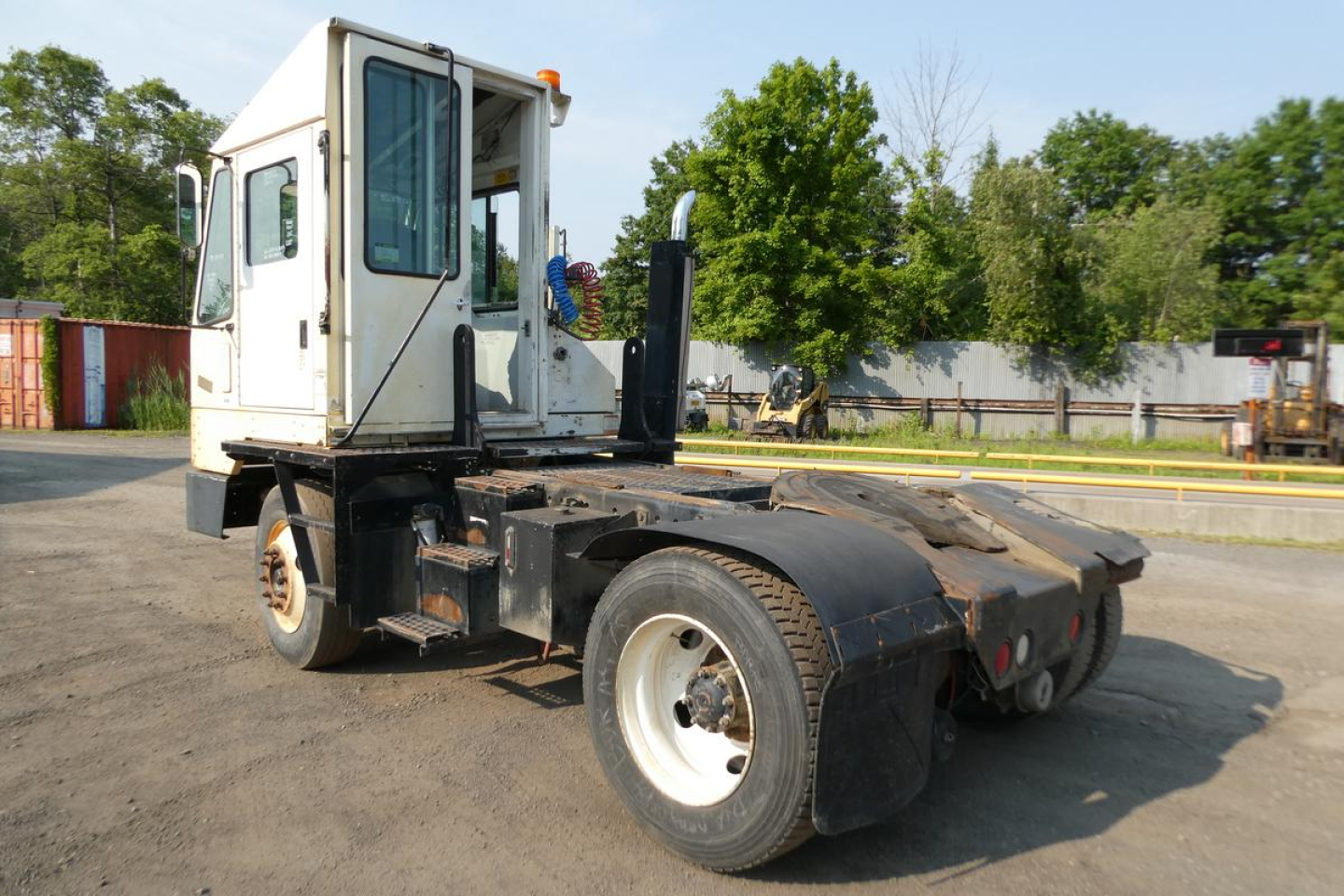 Kalmar Ottawa YT30 yard truck chassis with white cab, black undercarriage, and rear wheel fenders. Visible components include a cabin, driver's door, side window, steps, and a flat-deck frame with fifth-wheel area.