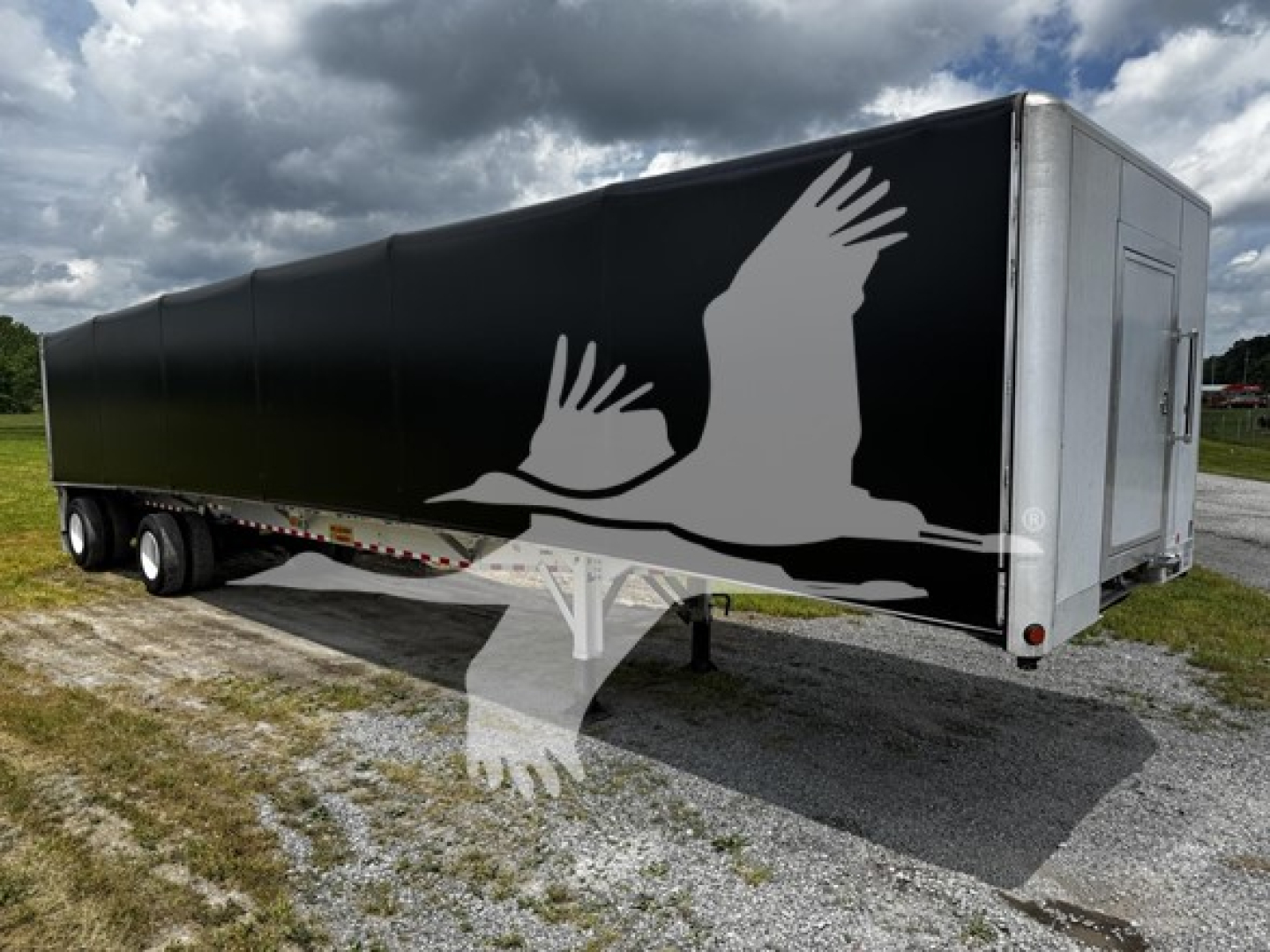 Trailer side view showing black curtainside with white bird graphic and silver front/rear corners.
