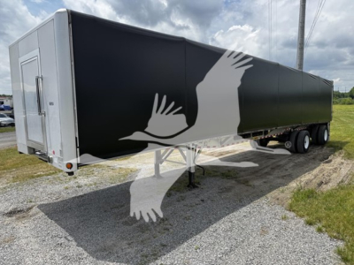 2018 Reitnouer Big Bubba curtainside trailer with black side panel and white rear end, three-axle configuration, in a gravel lot.