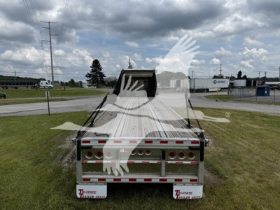 Trailer rear view showing big bubba curtain side trailer with taillights and rear bumper; visible text on bumper area reads 'Transcraft' and 'Trailer' logos. Opened tailgate and reflective strips along sides.