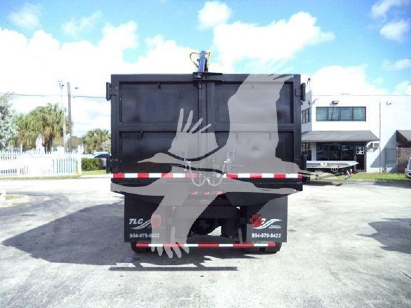Dump truck bed back showing rear lights and hitch area with graphic silhouette of a hand and a face on the dump bed.