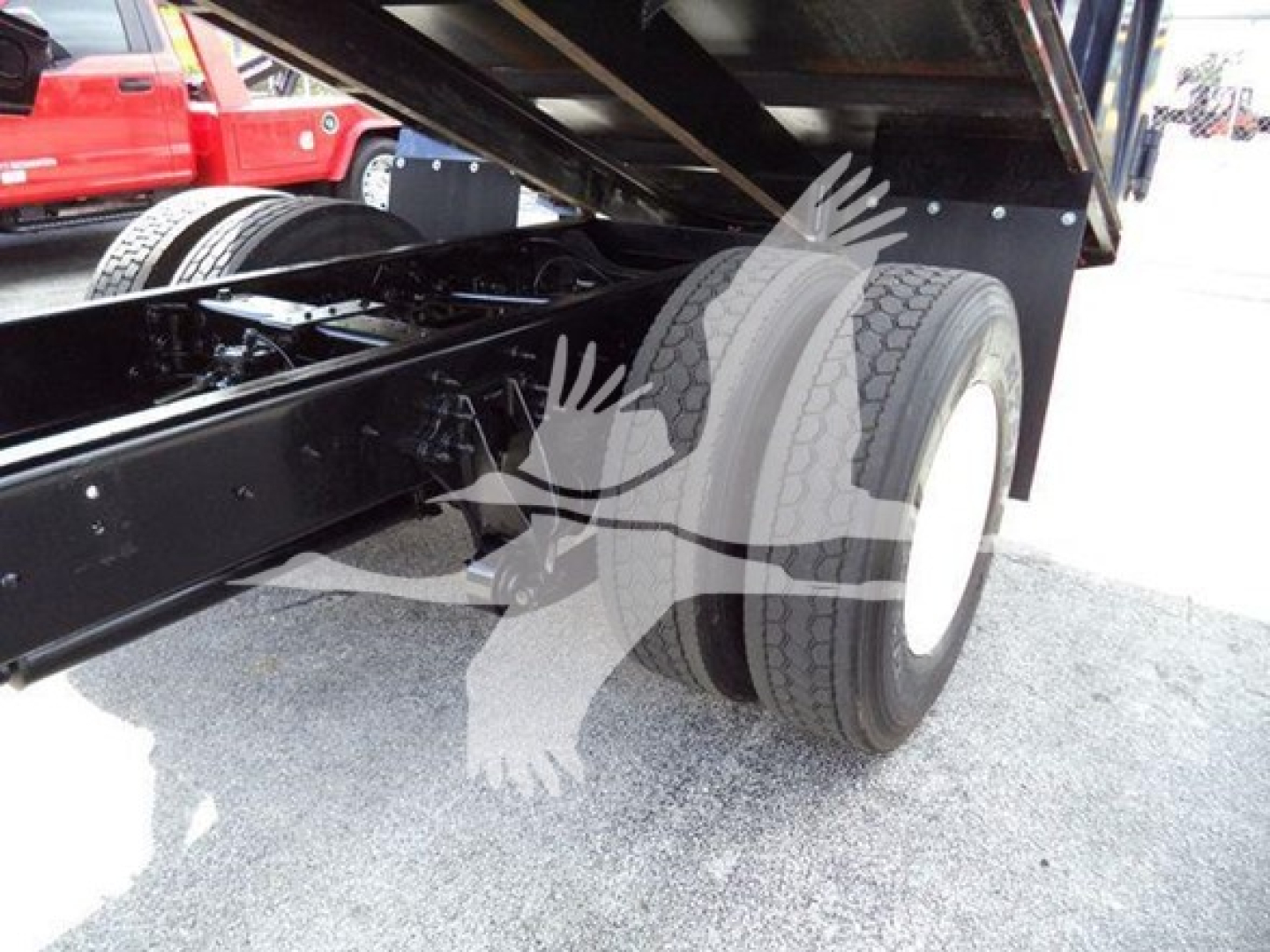 Truck rear dual wheels and undercarriage showing suspension frame and dump bed with hydraulic support.