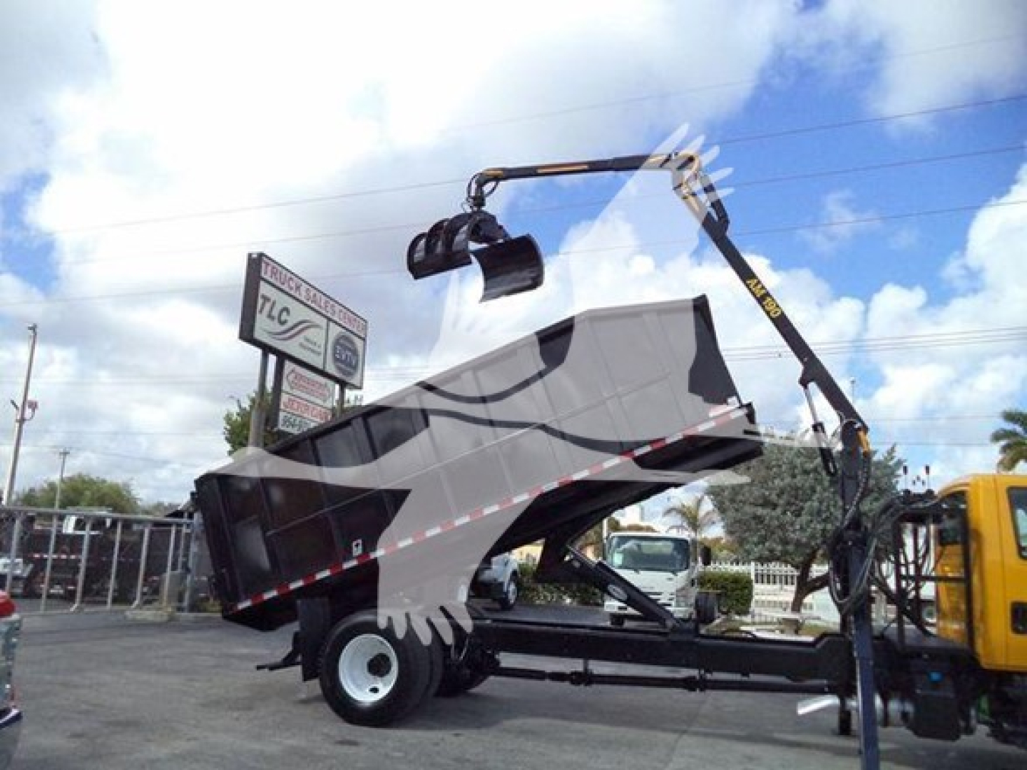Truck bed with grapple crane attached, 2019 International Durastar, side view showing crane arm, loading grapple, and trailer bed in a yard.