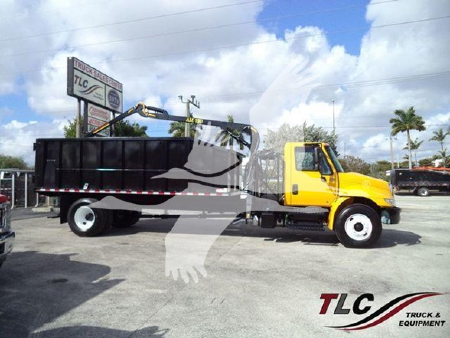 Dump truck side view showing a yellow International Durastar grapple truck with black dump bed, VIN 1HTMMMML6KH514931, stock T14931, in-service vehicle.