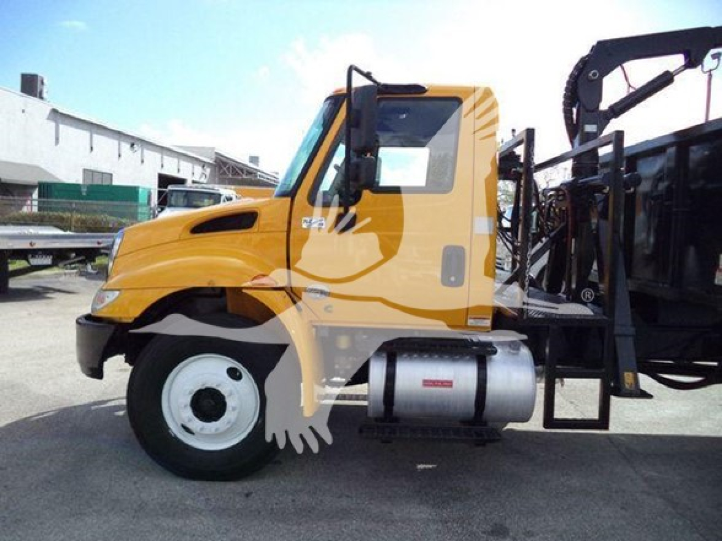 Grapple truck cab and front wheel of a 2019 International Durastar in yellow with black crane equipment behind.