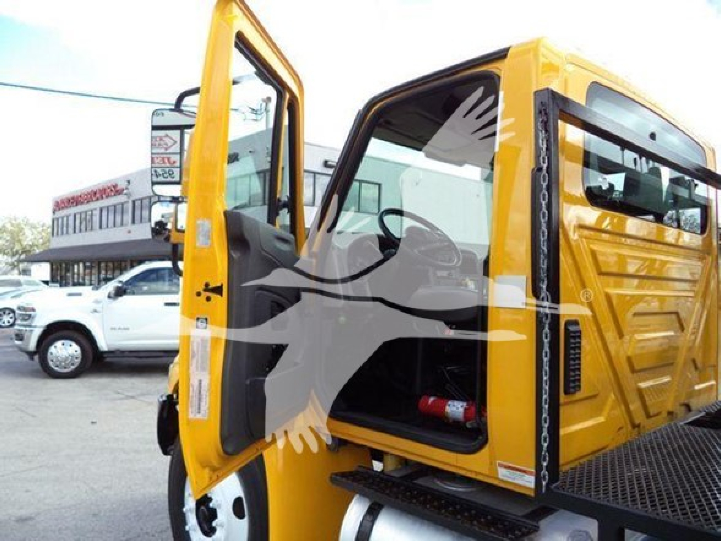 Yellow 2019 International Durastar grapple truck with open driver door, showing interior cab and mounted grapple equipment.