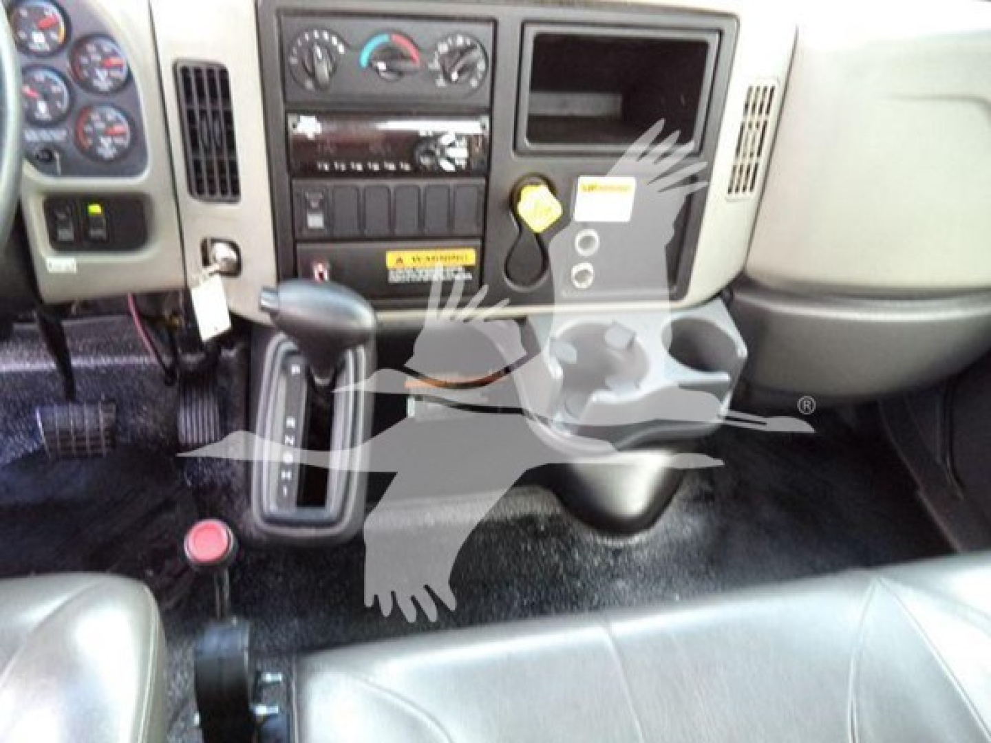 Truck cab interior showing center console with climate controls, radio, gear selector, cup holders and dashboard; Accidental watermark overlay visible.