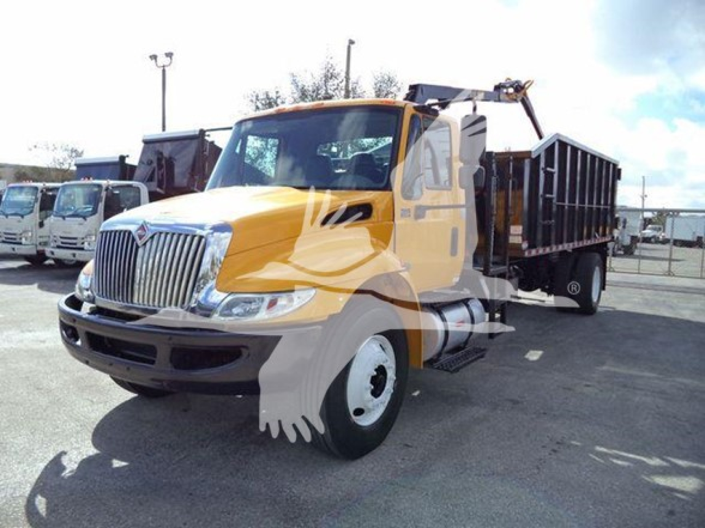 International Durastar dump truck with grapple setup, yellow cab, chrome grille, black dump bed, side view in lot.