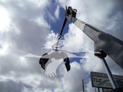 Hydraulic crane grapple attachment in operation on a truck crane with a sky backdrop.