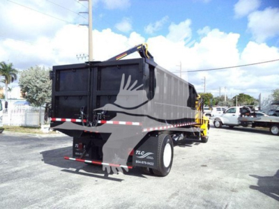 Truck bed with grapple apparatus on a 2019 International Durastar, side/rear view, black dump body, hydraulic grapple arm visible.