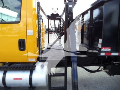Truck cab side and crane grapple apparatus on a 2019 International Durastar, with hydraulic lines and metal steps visible.