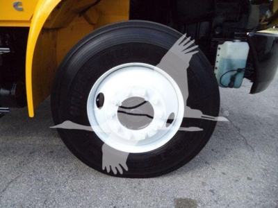 Wheel of a 2019 International Durastar grapple truck with black tire and white wheel rim; yellow body visible and water reservoir in background.