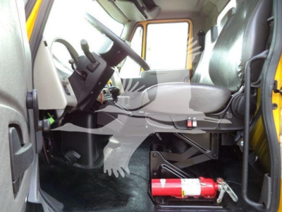Truck cab interior with steering wheel, driver seat, and a red fire extinguisher mounted under the dashboard visible.