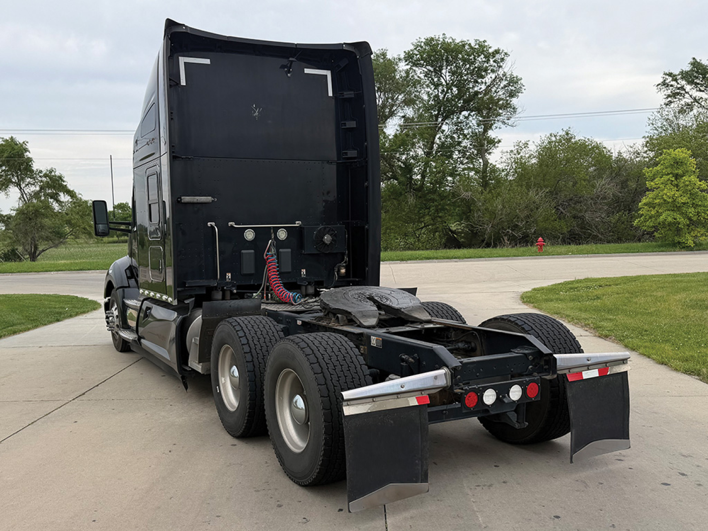 Kenworth T680 tractor rear view showing chassis and fifth wheel with dual rear axles and mud flaps.