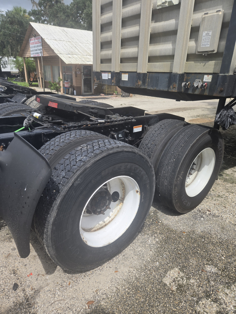 Truck rear dual wheels and fifth wheel area of a 2019 Freightliner Cascadia Day Cab tandem tractor showing dual rear axle tires and trailer hitch area.