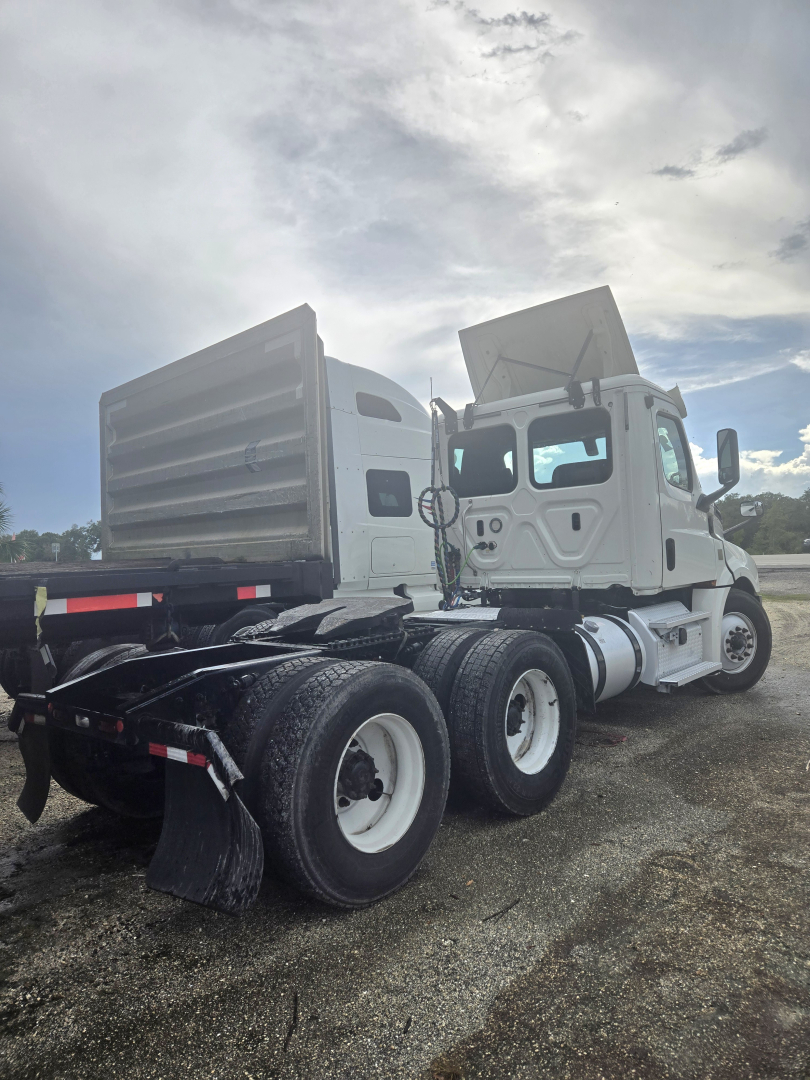 Truck side view showing cab and dual rear axles of a Freightliner Cascadia day cab tractor.